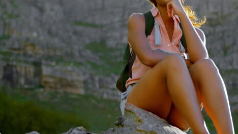 Female-hiker-relaxing-on-rock-at-countryside-4k