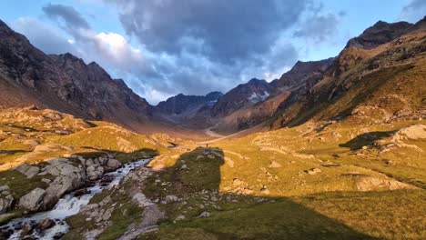 country side time-lapse - small blue stream , rocky mountain with vegetation and blue sky at golden hour