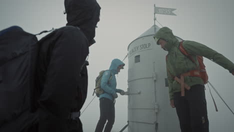 hikers arriving at the top of mountain triglav and looking at aljaž tower and opening it