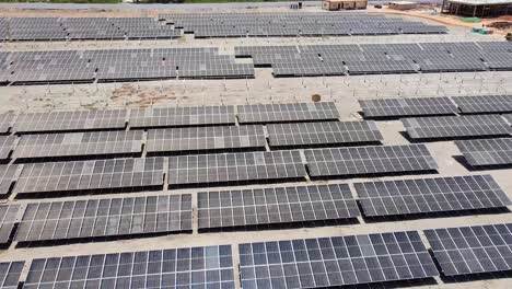 Aerial-forward-flying-over-dirty-dusty-bifacial-solar-panels-at-Jambur-solar-photovoltaic-energy-project-site-under-construction-in-Gambia