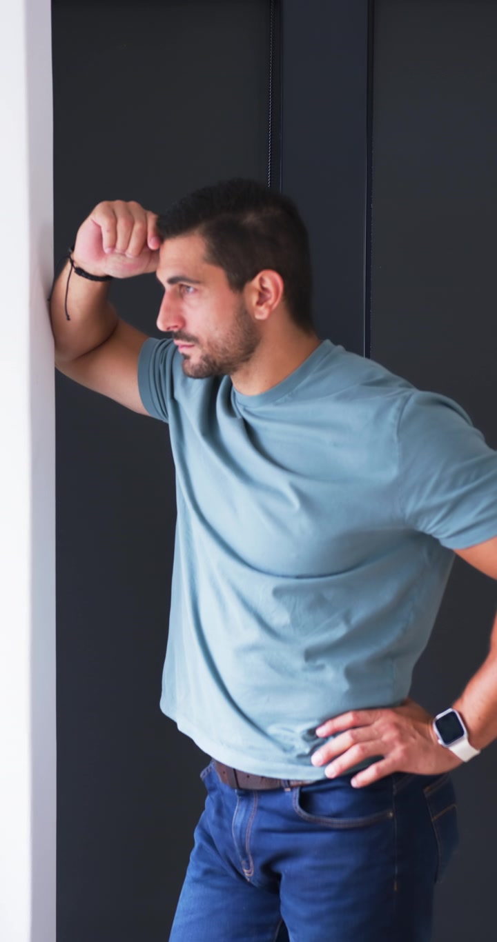 Video verticale: Uomo adulto che fa una pausa, appoggiato allo stipite della porta nel corridoio, gesticolando e poi strofinandosi il naso per riposare.