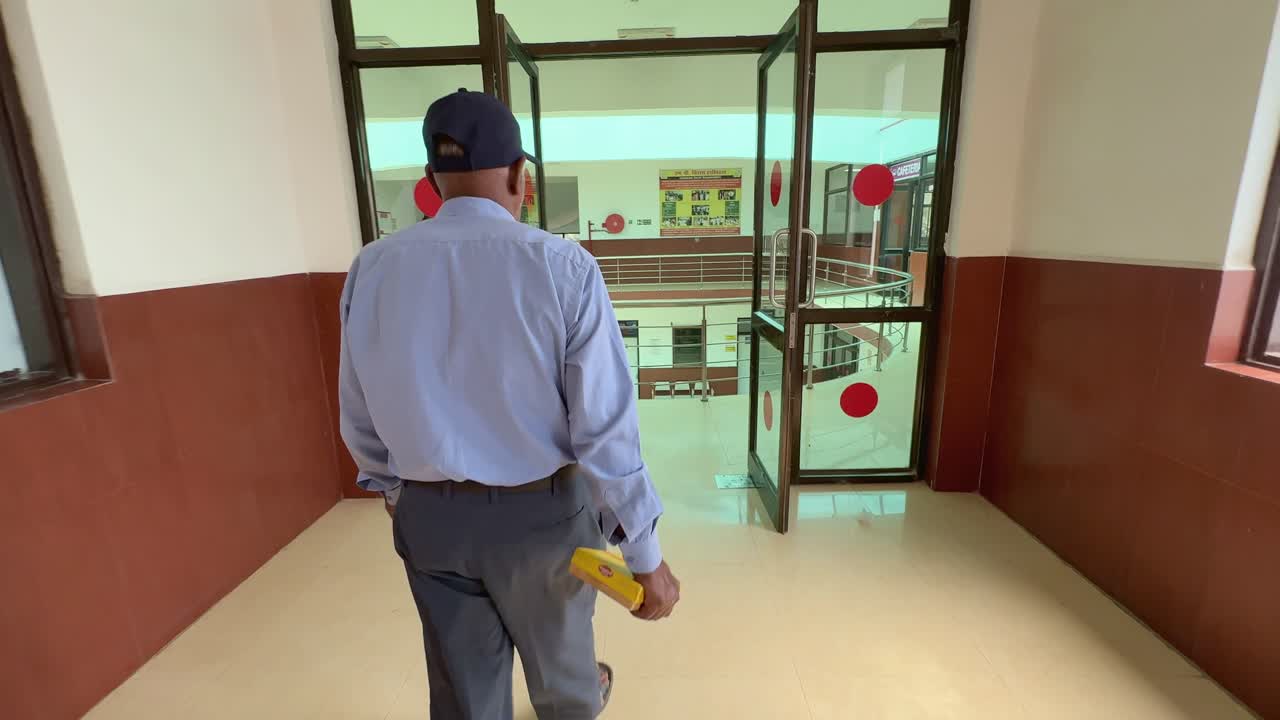 wide angle over the shoulder shot of a man walking through the corridor or passage in slow-motion, happy man walking with a box of sweet at the corridor after hearing a good news