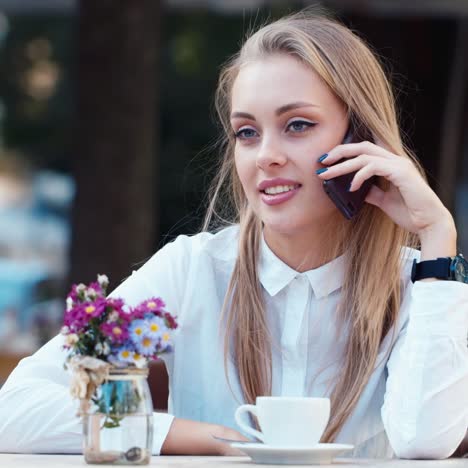 Attractive-woman-rests-in-a-cafe-and-talks-on-the-phone