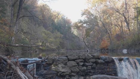 Water-flowing-over-waterfall,-through-rocks-and-autumn-leaves-in-Wissahickon