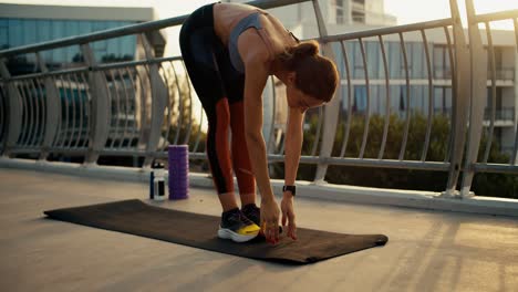 A-girl-in-a-sports-summer-uniform-is-doing-morning-yoga-on-a-special-black-rug-on-the-street.-Morning-exercise-on-the-street