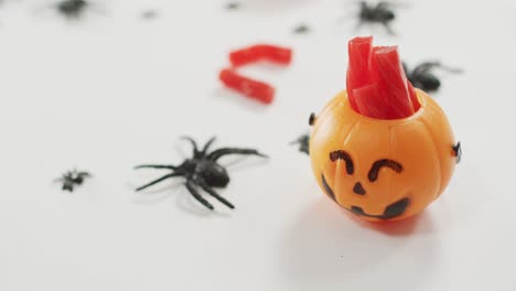 Candies-in-scary-halloween-pumpkin-printed-bucket-and-spiders-toys-against-grey-background