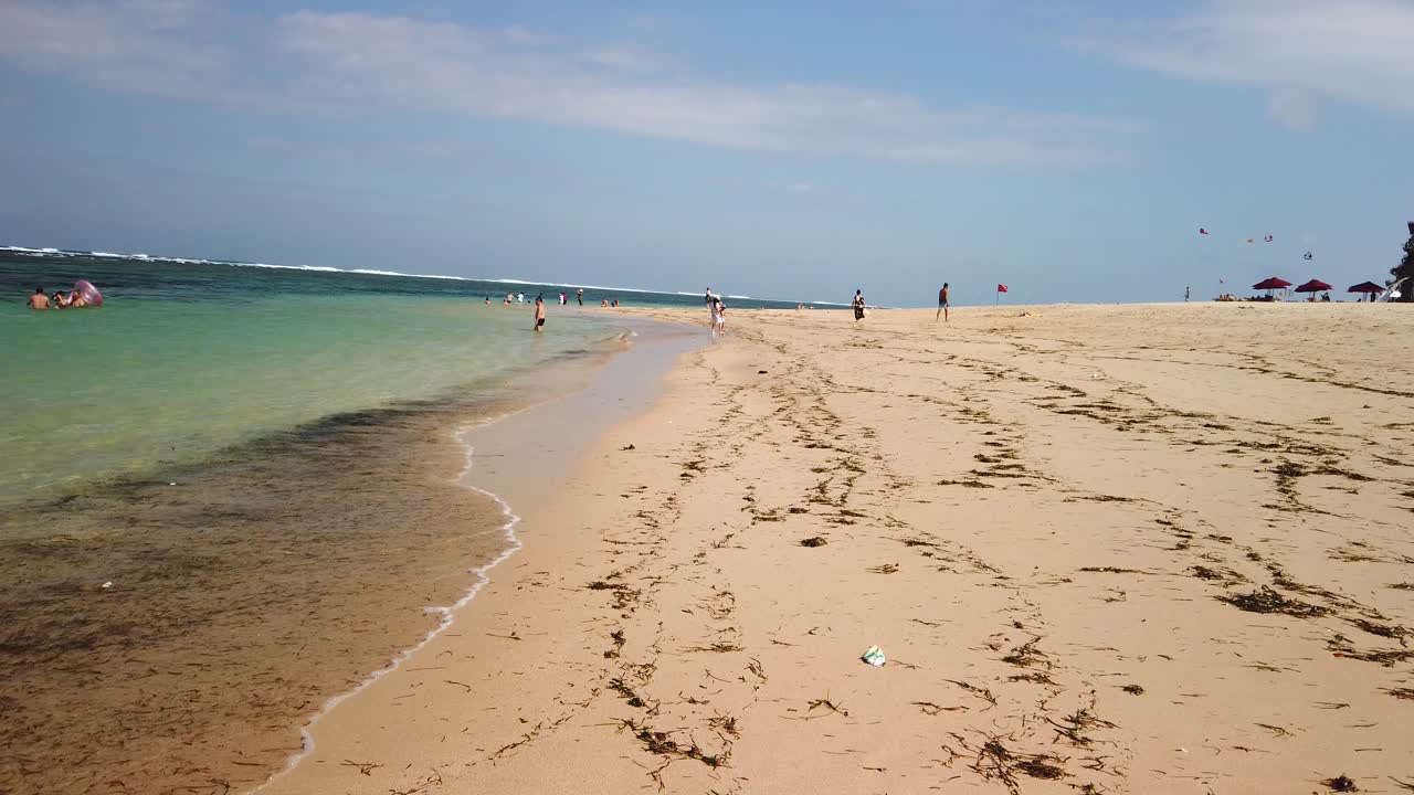 Walking around on Nusa Dua beach on sunny windy summer day with ocean blue in background and amazing yellow sandy beach.