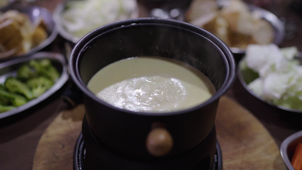 Argentine Bagna Cauda bubbling at table with vegetables and bread, traditional food sharing moment