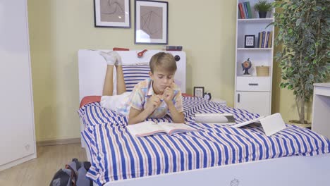 the child is lying on his bed, studying.