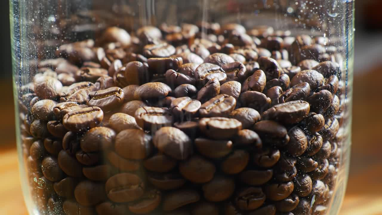 Close-up View of a Glass Container Filled with Whole Coffee Beans, Showcasing Their Rich Texture and Glossy Appearance Under Natural Light