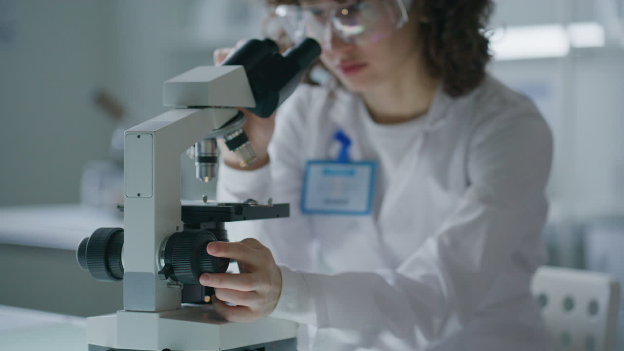Scientist Adjusting Microscope Focus in Research Laboratory