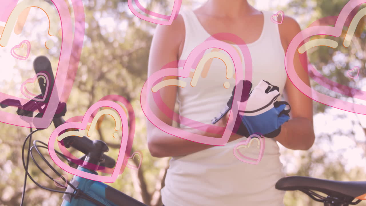 Adjusting gloves, cyclist with animation of pink hearts overlaying in school