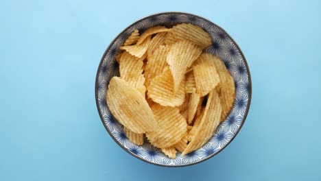 la mano recogiendo un chip de patata de un cuenco de papas fritas