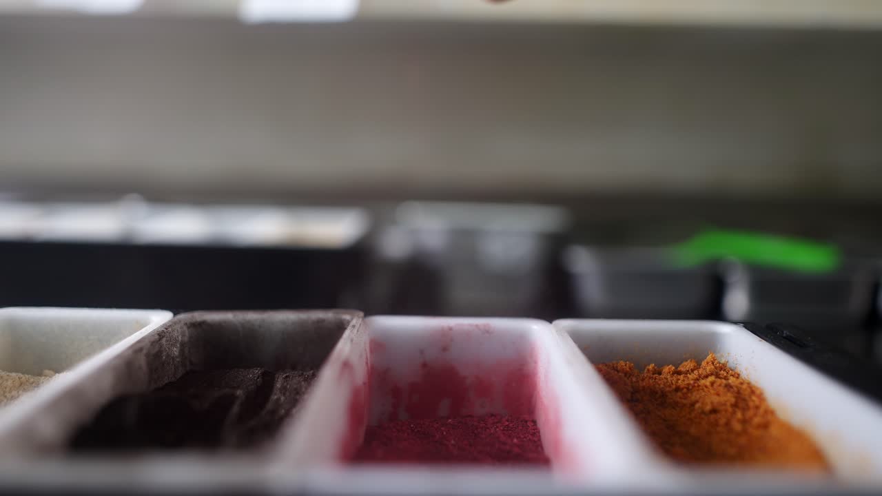 Slow motion and close up view of Red powder condiment falling in an ingredients container.