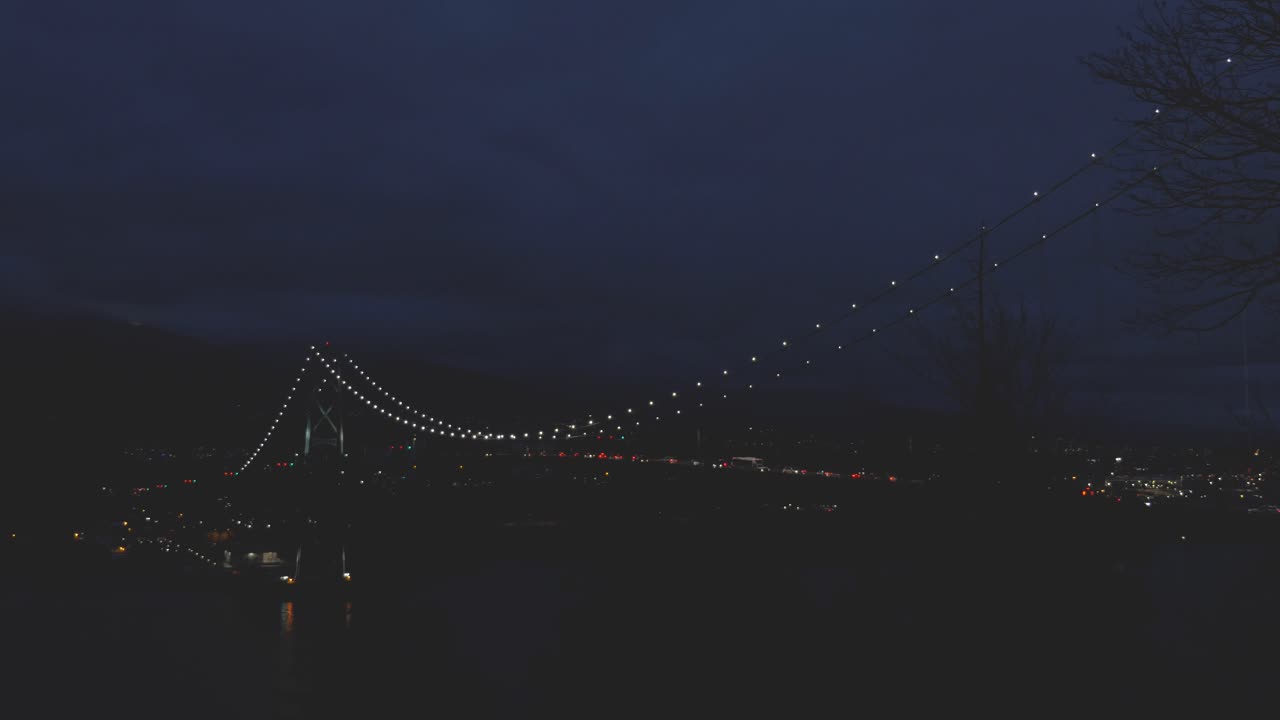 Lion's gate bridge connecting Vancouver bc to North Vancouver from stanley park at night with traffic lights moving across spanning over ocean inlet slow pan left to right creepy peaceful dark relax