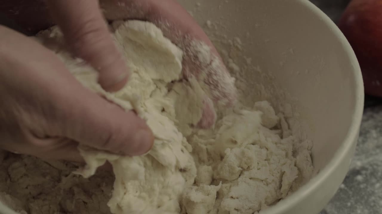 Hands mixing dough in a bowl close up shot
