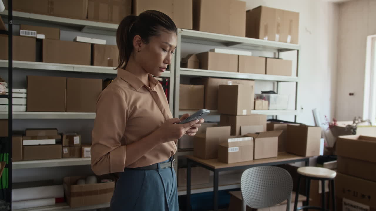 Manager Counting Parcels and Checking Smartphone at Storage Office