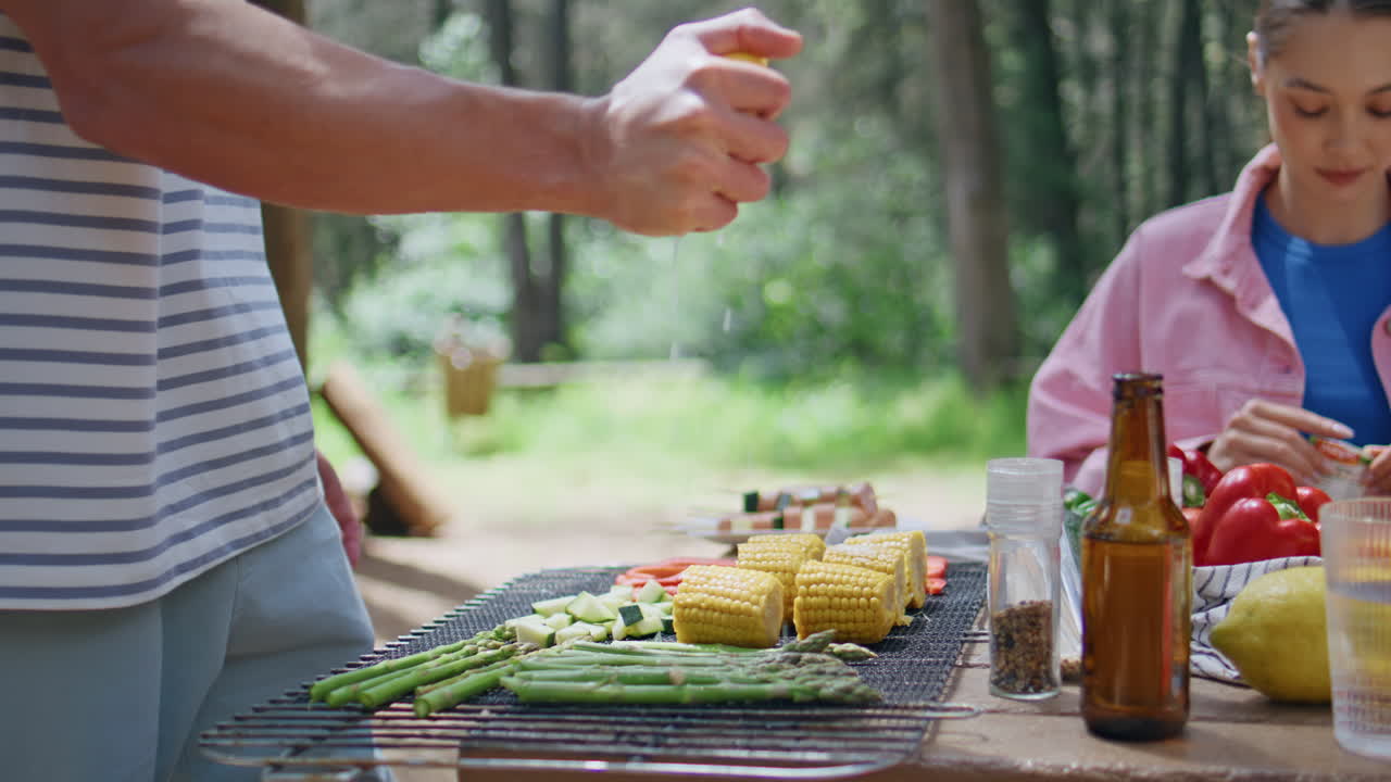 Unknown man grilling vegetables at outdoor barbecue in sunny forest closeup