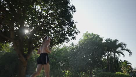 man jogging shirtless outdoors among trees