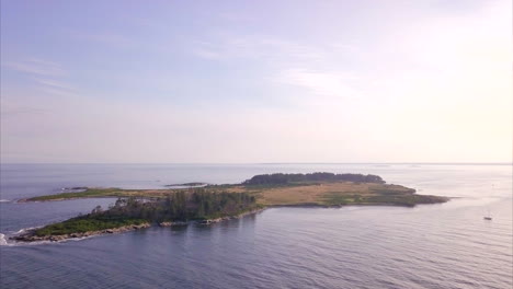 Aerial-shot-flying-over-the-deep-blue-Atlantic-ocean-orbiting-around-Richmond-Island-from-Kettle-Cove-Beach,-Maine