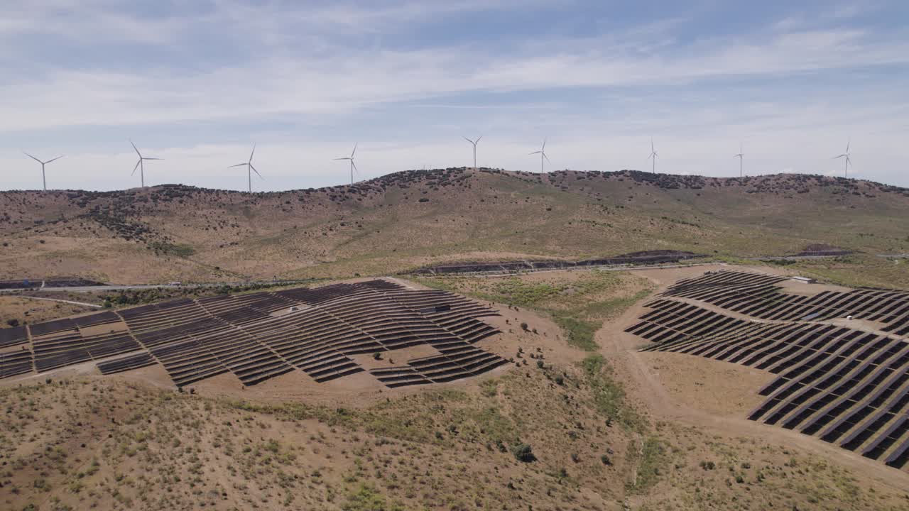 Aerial: Plasencia's solar panels and wind turbines on the skyline, Spain