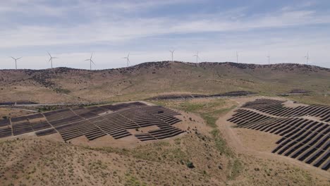 Aerial:-Plasencia's-solar-panels-and-wind-turbines-on-the-skyline,-Spain