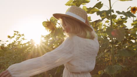 Schöne-Junge-Frau-Mit-Strohhut-Und-Weißem-Kleid-Im-Landhausstil,-Die-Bei-Sonnenuntergang-Im-Sonnenblumenfeld-Lächelt-Und-Tanzt