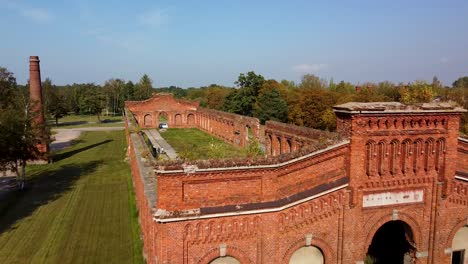 Aerial-view-of-former-russian-tsar-army-gymnastics-hall-in-Karosta,-Liepaja,-used-for-gymnastics-performances-and-competitions-for-horseback-riders,-wide-angle-drone-shot-moving-backwards