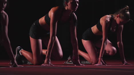 three sports girl athletes at night on the treadmill start for the race at the sprint distance from the sitting position