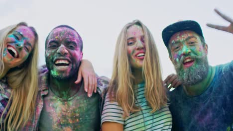 jóvenes multiétnicos felices chicas y chicos divirtiéndose, abrazándose y sonriendo a la cámara mientras celebran las vacaciones de holi