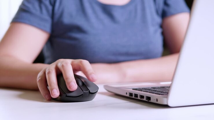 Donna che lavora al portatile e usa un mouse wireless