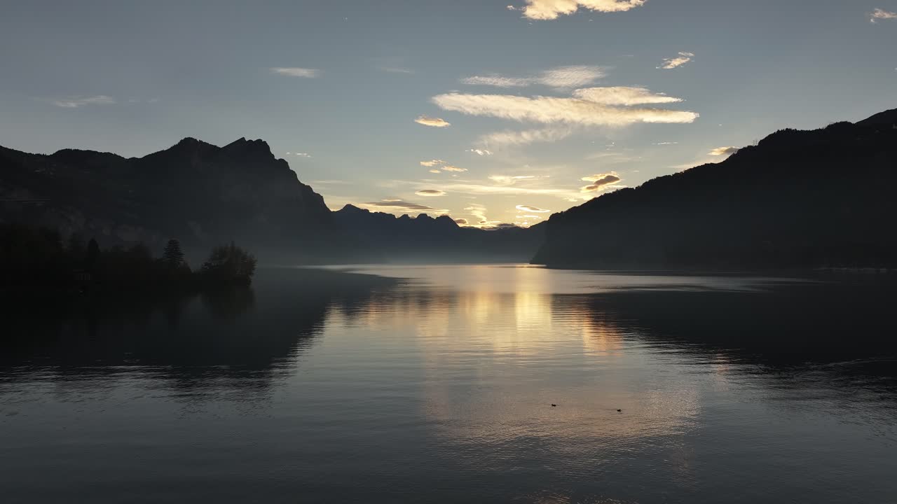 Serene sunrise over calm lake with mountain reflections at Walensee, Switzerland