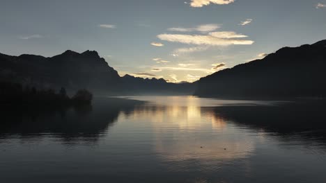 serene sunrise over calm lake with mountain reflections at walensee, switzerland