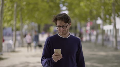hombre sonriente usando el teléfono móvil al aire libre