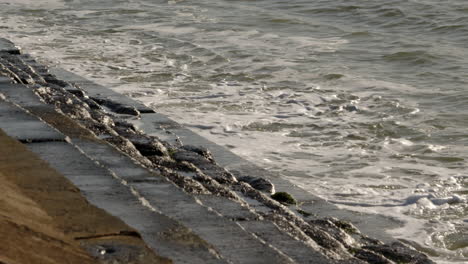 Zeitlupenaufnahme-Von-Wellen,-Die-Auf-Die-Küstenschutzanlagen-In-Milford-On-Sea-Krachen