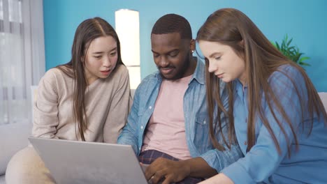 multiethnic group of friends working on laptop at home.