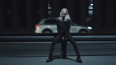 Laughing-woman-night-highway-siiting-on-bench-at-night-on-dark-road-in-city.