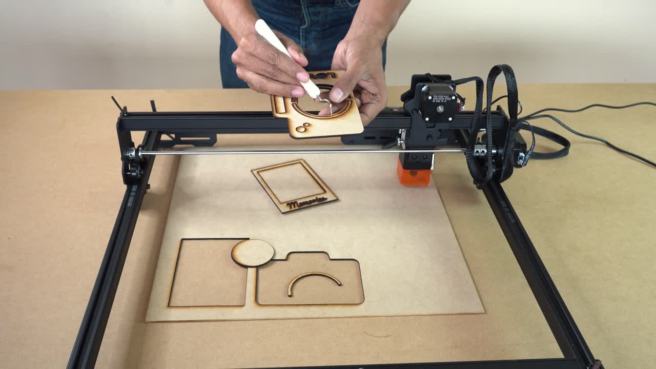 Demonstration of laser cutting results as a man holds finished pieces and shows details of the cut