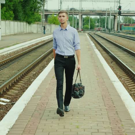 a good-looking young businessman walks along the railway platform 1