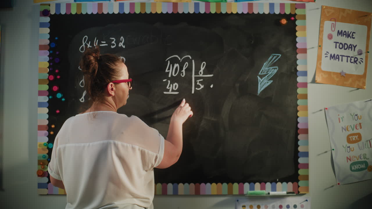 Back View of Female Teacher Writing Multiplication Table on the Chalkboard