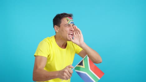 Man cheering for South Africa waving a national flag looking away