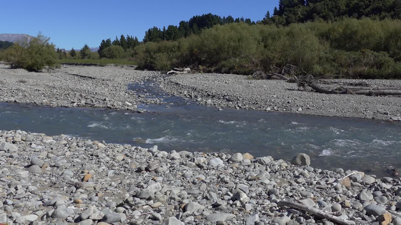 caminando hacia el río mientras el agua blanca aparece sobre las rocas sumergidas - río kowai, canterbury