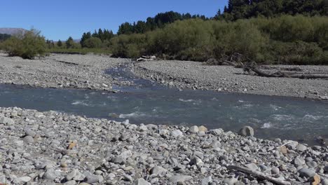 Walking-towards-river-as-white-water-appears-above-submerged-rocks---Kowai-River,-Canterbury