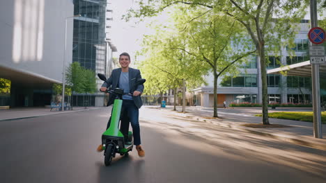 man riding a green electric scooter in a modern city street
