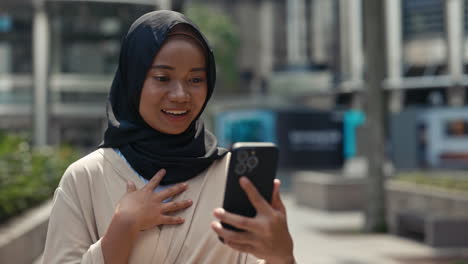 young muslim woman engaged in video call on smartphone outdoors