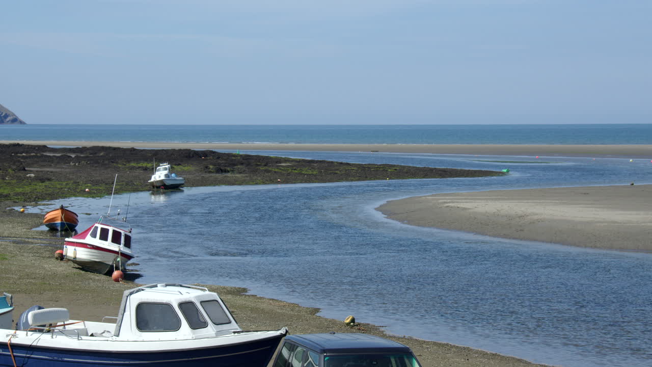 Panning shot of Parrog beach and river Nyfer at Newport sands. With cars and boats