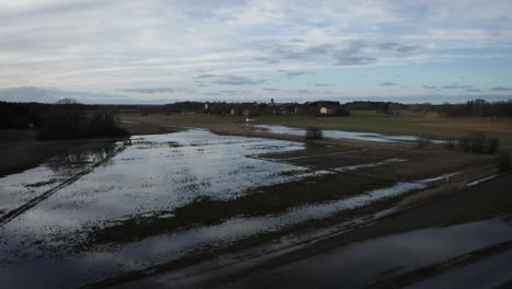 Aerial shot of flooded fields close to suburban buildings