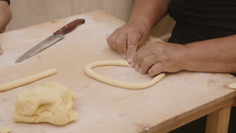 slow motion footage of a lady in italy rolling dough to make pasta shells and cutting the roll