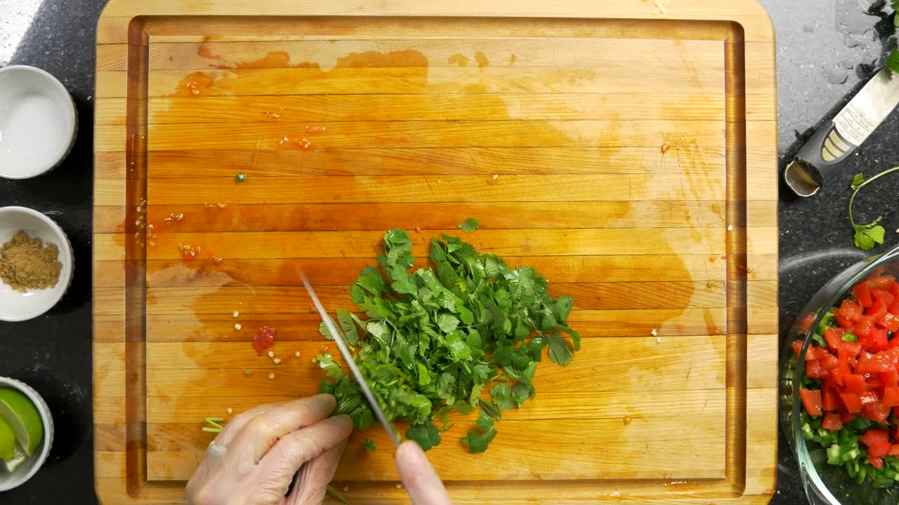 Overhead shot of chopping green cilantro on a wood cutting board