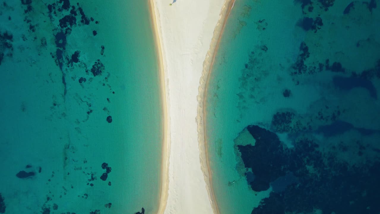 Panoramica aerea dall'alto della spiaggia di Kolona e della lingua di sabbia curva, acqua turchese vibrante che circonda entrambi i lati, ascesa